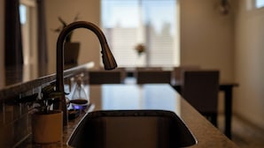 Une cuisine dotée d’un robinet moderne, d’un évier et d’une fenêtre en arrière-plan.