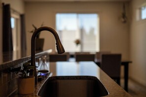 Une cuisine dotée d’un robinet moderne, d’un évier et d’une fenêtre en arrière-plan.