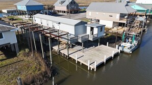 En fastighet vid vattnet med en brygga, en liten båt och flera byggnader, inklusive ett stort hus och mindre byggnader.