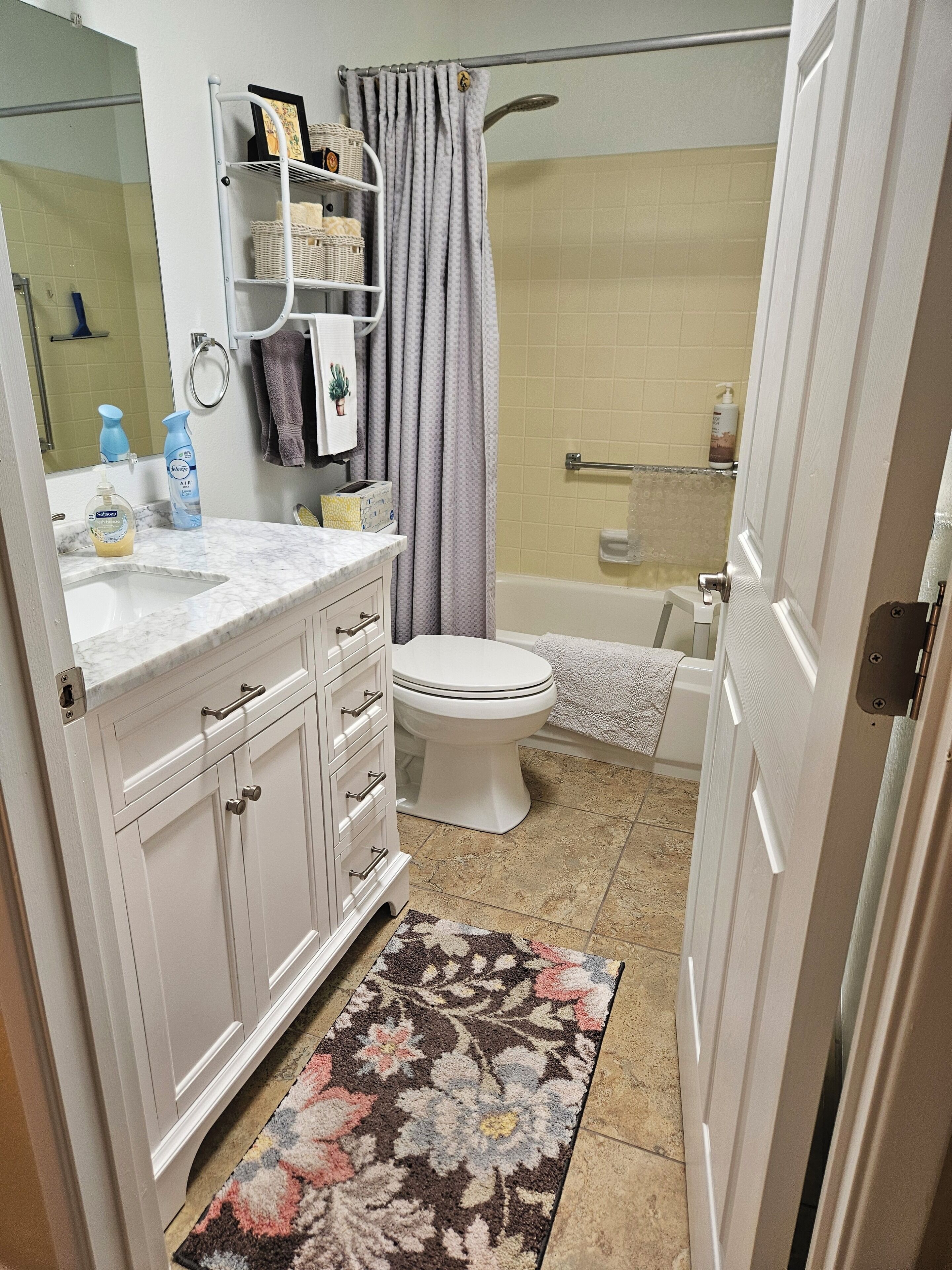 A bathroom with a white sink, toilet, and bathtub. There are toiletries on the counter and a shower curtain.