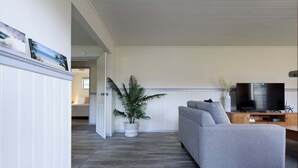 Un salon avec un canapé gris, un téléviseur et une plante en pot.