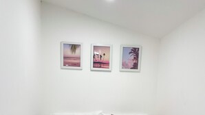 A small, neatly arranged bedroom with a single bed, white bedding, and three framed pictures on the wall. - Charming studio close to downtown Fort Myers and Edison and Ford winter estates! (Fort Myers)
