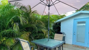 An outdoor patio with a table and chairs, surrounded by lush greenery. - Charming studio close to downtown Fort Myers and Edison and Ford winter estates! (Fort Myers)