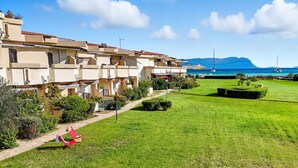 Un hôtel situé sur la côte, composé de plusieurs bâtiments à étages, doté d’une pelouse bien entretenue et offrant une vue sur la mer et les montagnes en arrière-plan.
