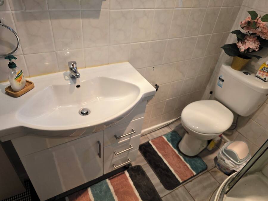 Un baño con lavamanos blanco, inodoro y zona de ducha.