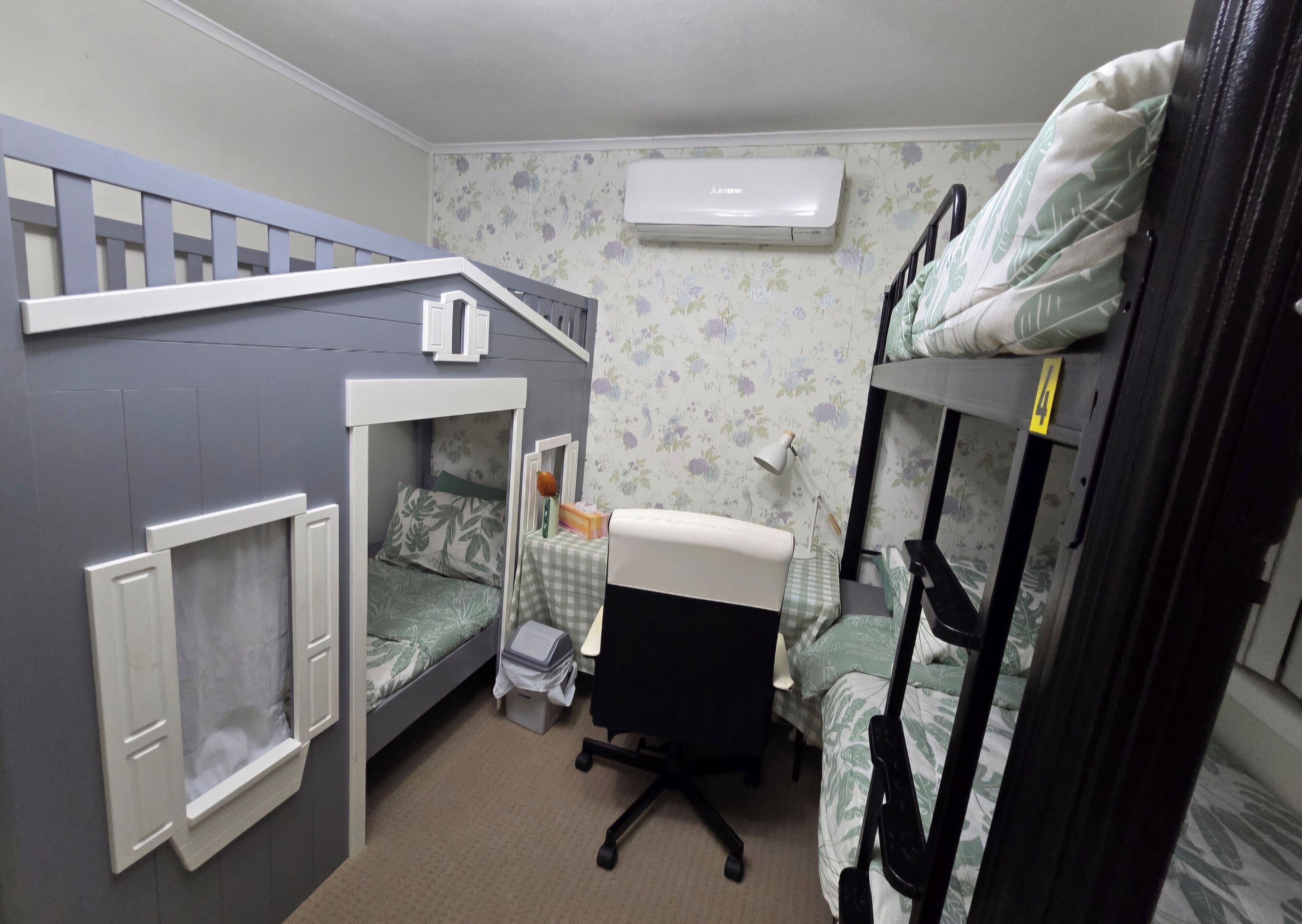 Una habitación pequeña con literas, un escritorio, una silla y un aire acondicionado.