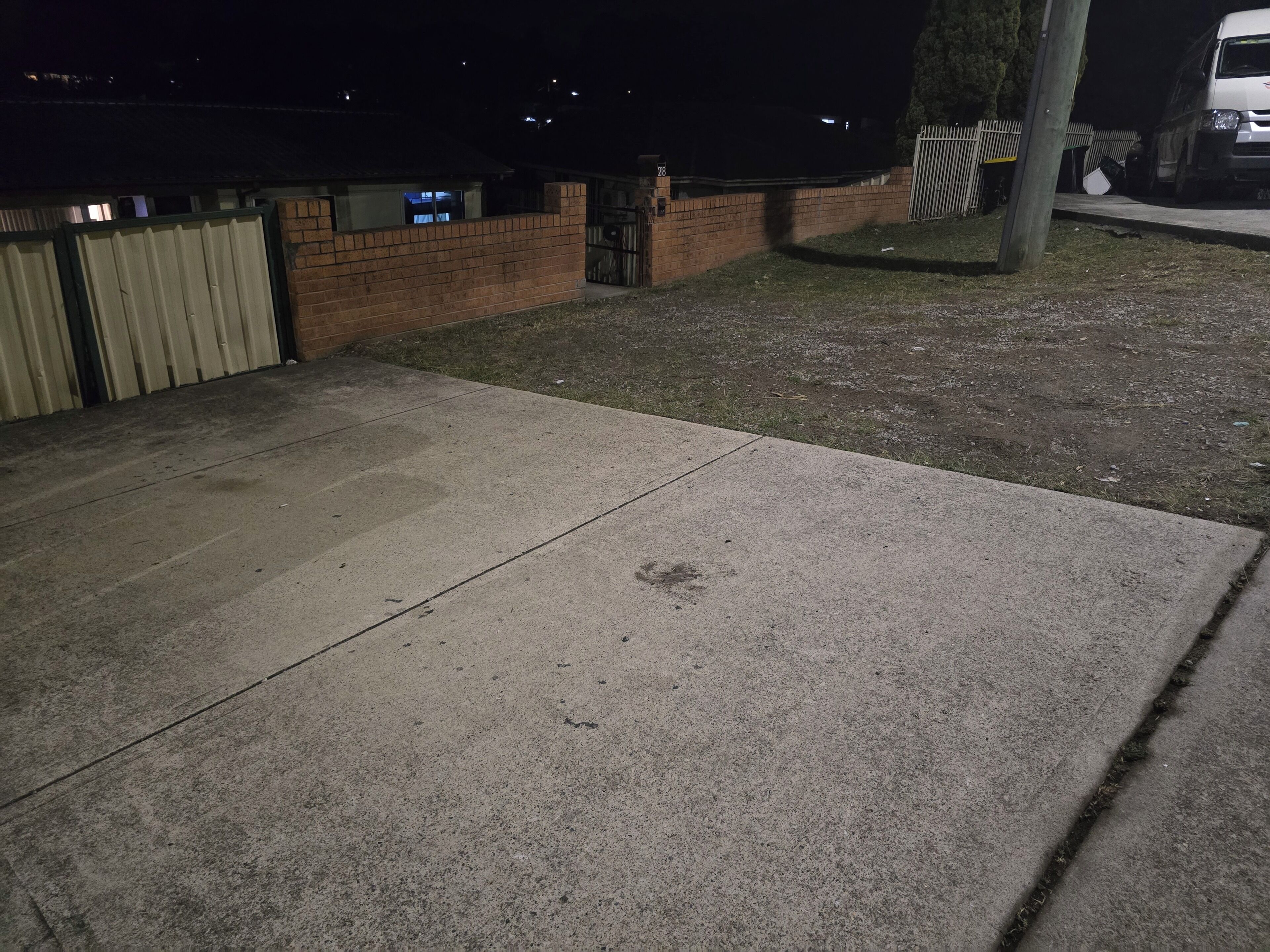 A concrete patio area with a brick wall and a metal gate.