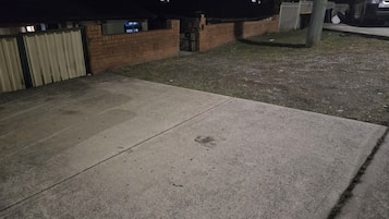 A concrete patio area with a brick wall and a metal gate.