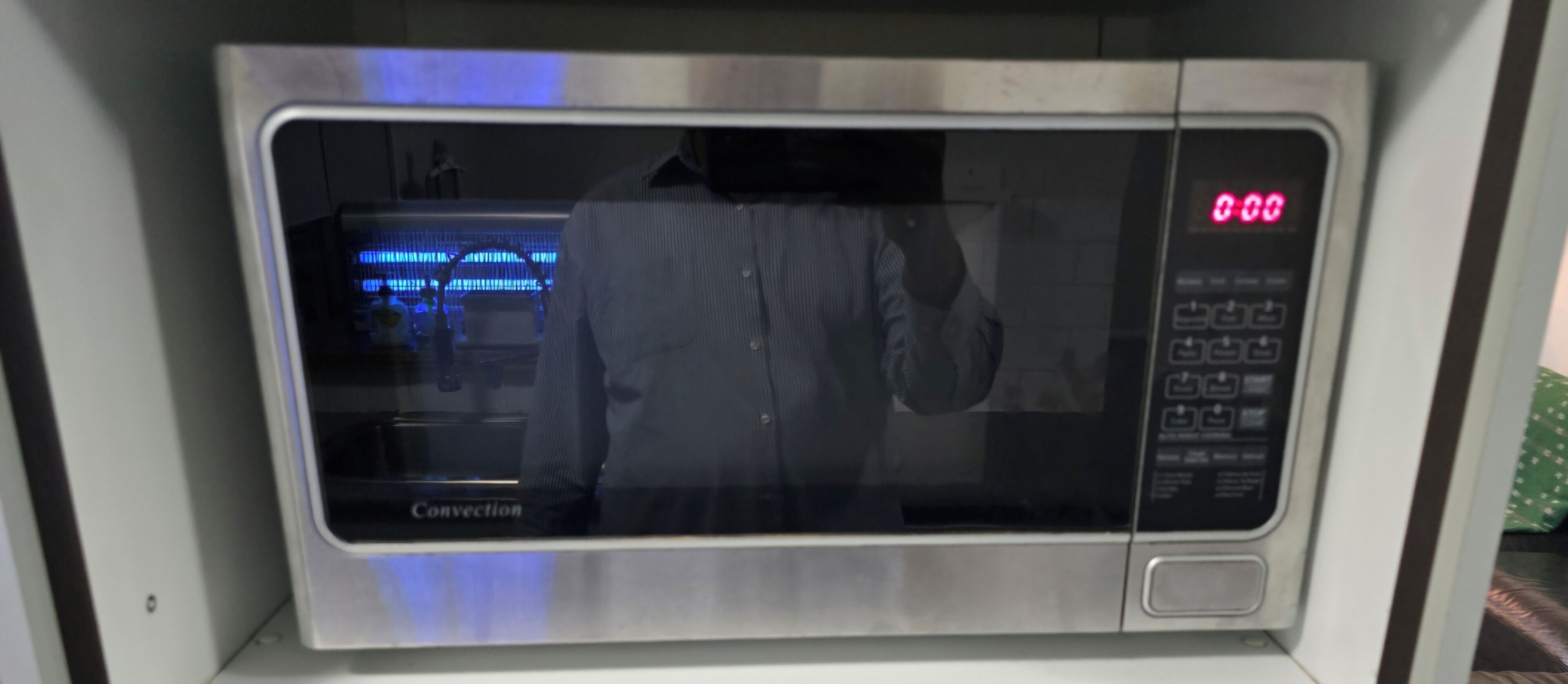 A stainless steel microwave with a digital display and control panel.