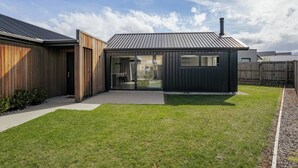 Et moderne hus med træfacade, et metal tag og en glasdør, der fører ud til en terrasse.