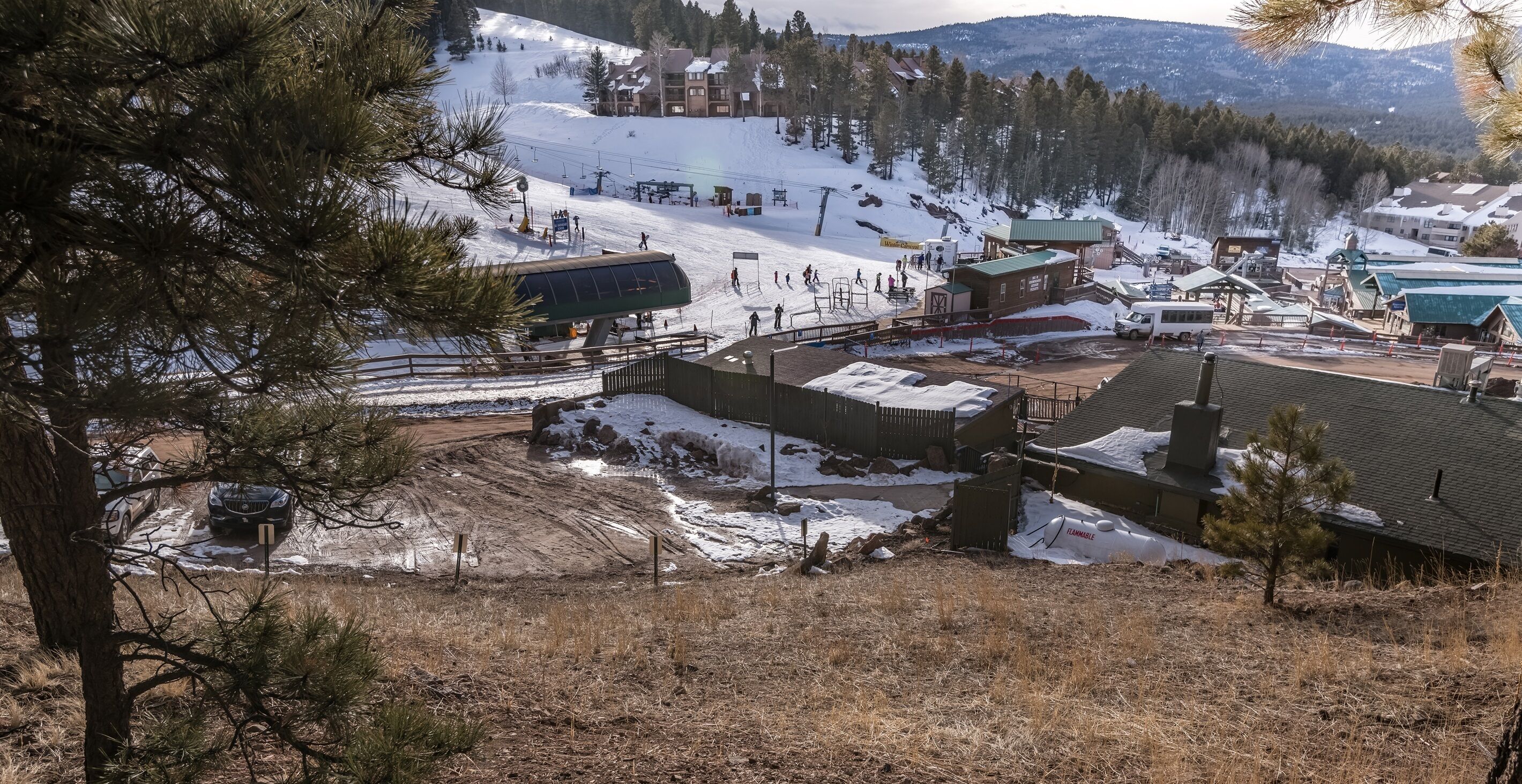 A ski resort with a chairlift, buildings, and a snowy landscape.