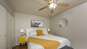 A bedroom with a bed, a ceiling fan, a bedside table with a lamp, a mirror, and a picture on the wall. - 3-Min Walk to Ski Lift | Mountain-View Chalet (Angel Fire)
