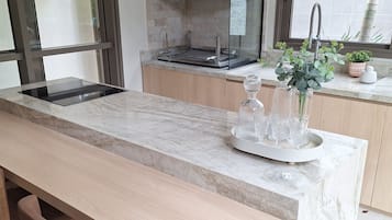 Uma cozinha moderna com bancada de mármore, cadeiras de madeira e fogão embutido.