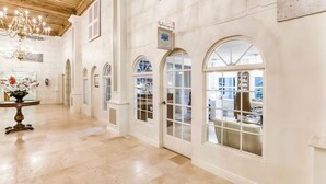 A corridor with arched windows, a chandelier, and a table with flowers.