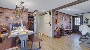 A dining area with a wooden table set for four, a chandelier, and a brick wall with a deer head decoration.