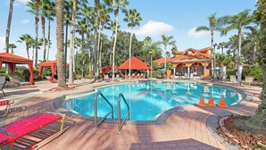 Ein Swimmingpool, umgeben von Palmen und Liegestühlen.