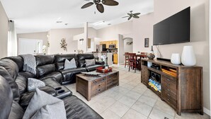 Ein modernes Wohnzimmer mit einem Ecksofa, einem Holztisch und einem an der Wand befestigten Fernseher.