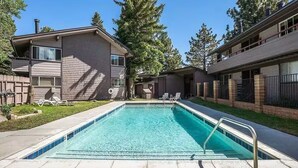 A rectangular swimming pool with a metal ladder, surrounded by a concrete deck. - Mountain Condo - 4 Beds with 2 Bath - Prime Location (Mammoth Lakes)