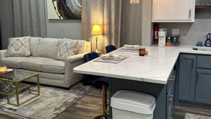 Et moderne køkken med marmor bordplade, en indbygget vask og et spiseområde med en sofa og et sofabord.