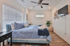 A bedroom with a bed, a ceiling fan, a TV, and a window with blinds. - Newly built 4BR, Steps to Beach, Grill/Balcony, Smart TVs & near SkyWheel! (Myrtle Beach)