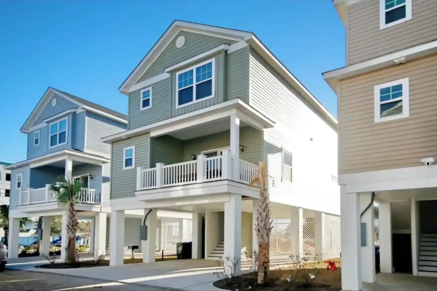A row of two-story townhouses with balconies, a covered front porch, and a clear sky.