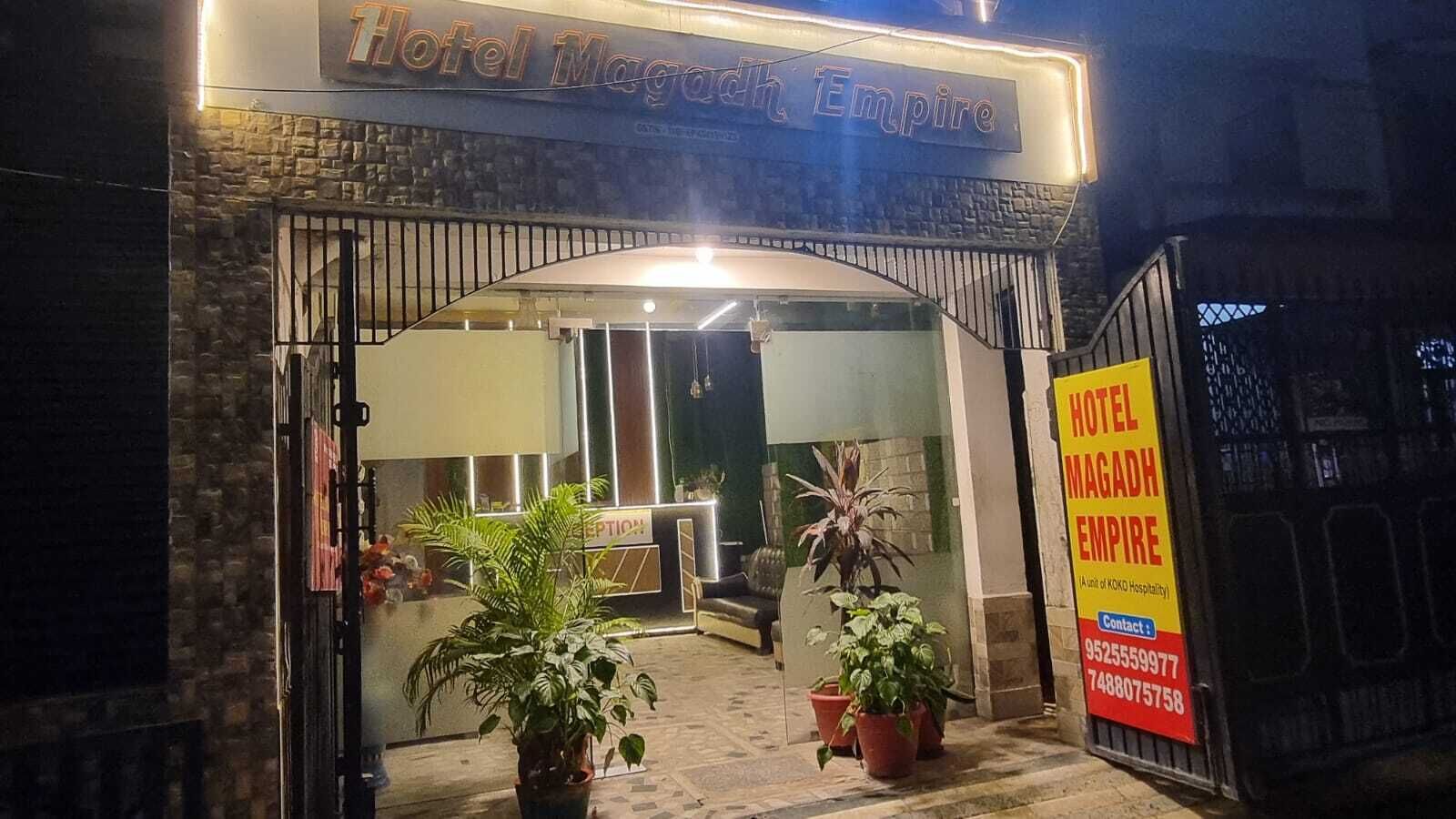 The entrance of Hotel Magadh Empire with a reception desk and potted plants.