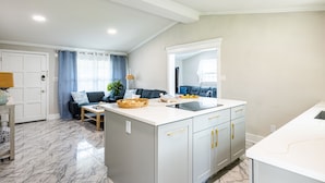 Een moderne keuken met een marmeren vloer, een centraal kookeiland en een zithoek met een bank en tafel.
