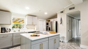 Een moderne keuken met marmeren vloeren, een groot eiland en geïntegreerde apparatuur.