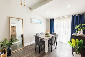 Un coin repas comprenant une table, des chaises, un miroir et une plante en pot.