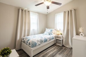 Une chambre à coucher bien rangée, avec un lit, une table de chevet et une petite table d’appoint.