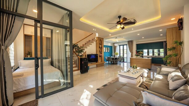 A modern living room with a sofa, a coffee table, and a TV. There is a staircase leading to another level.