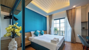 A modern bedroom with a large bed, a wooden desk, and a vase of flowers.