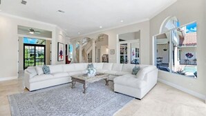 A spacious living room with a large sectional sofa, a coffee table, and a patterned rug. - Spacious 4 bedroom Coastal Luxury Retreat with Private Dock. (Marco Island)