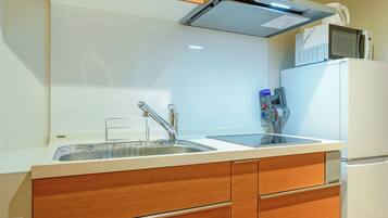 A compact kitchen with wooden cabinets, a stainless steel sink, and a microwave.