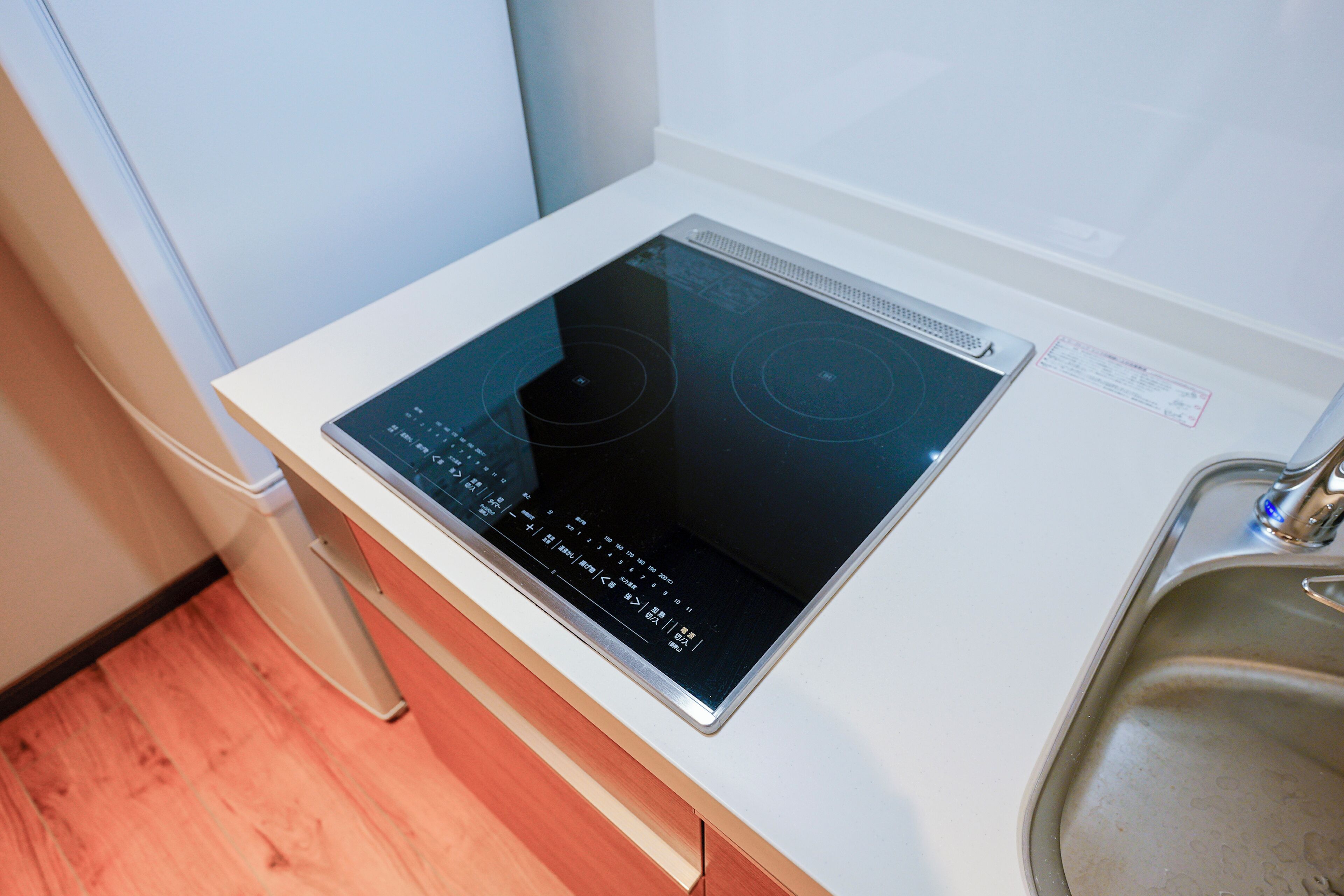 A kitchen with a built-in induction cooktop and a stainless steel sink.