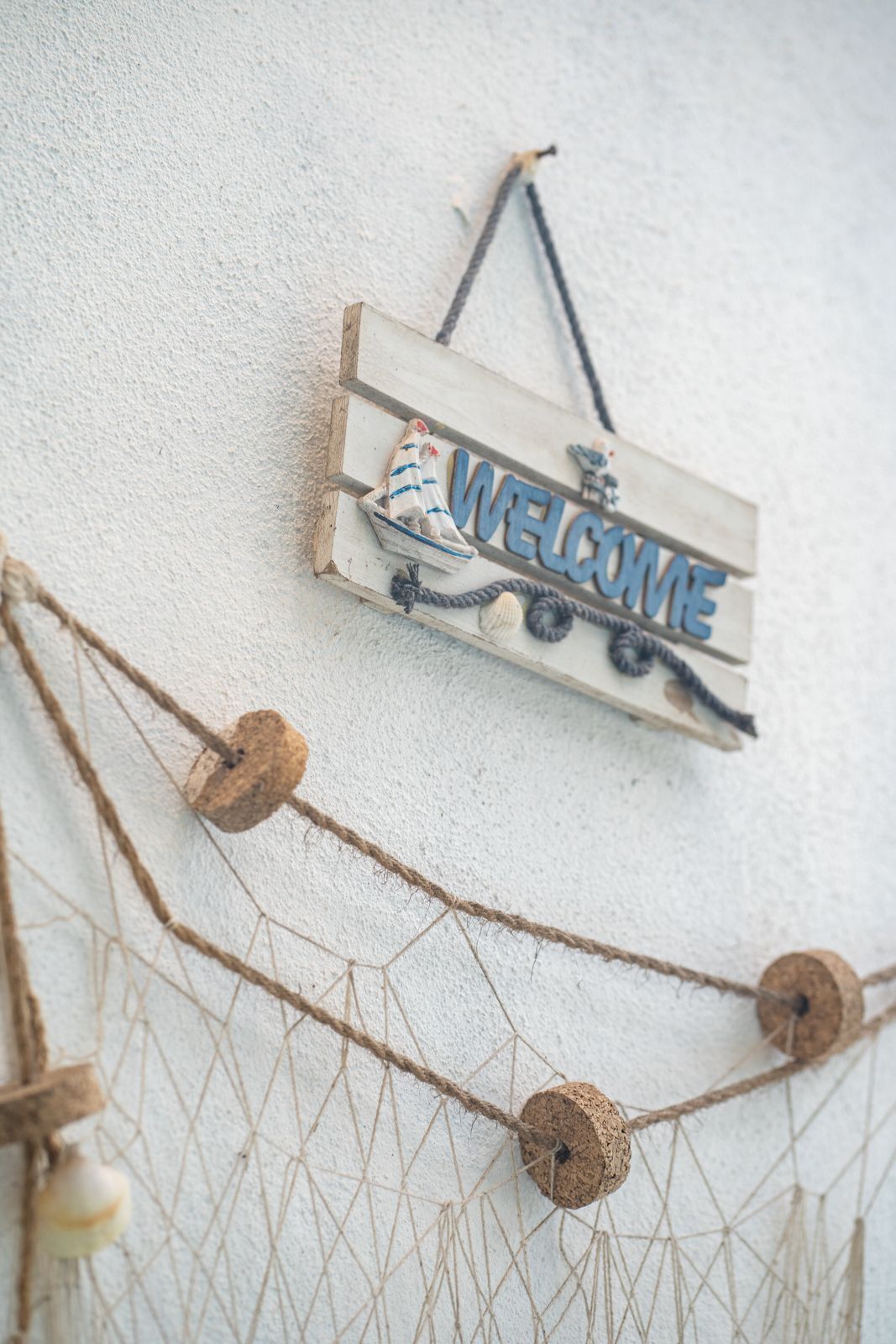 A welcome sign with nautical decorations on a textured wall.