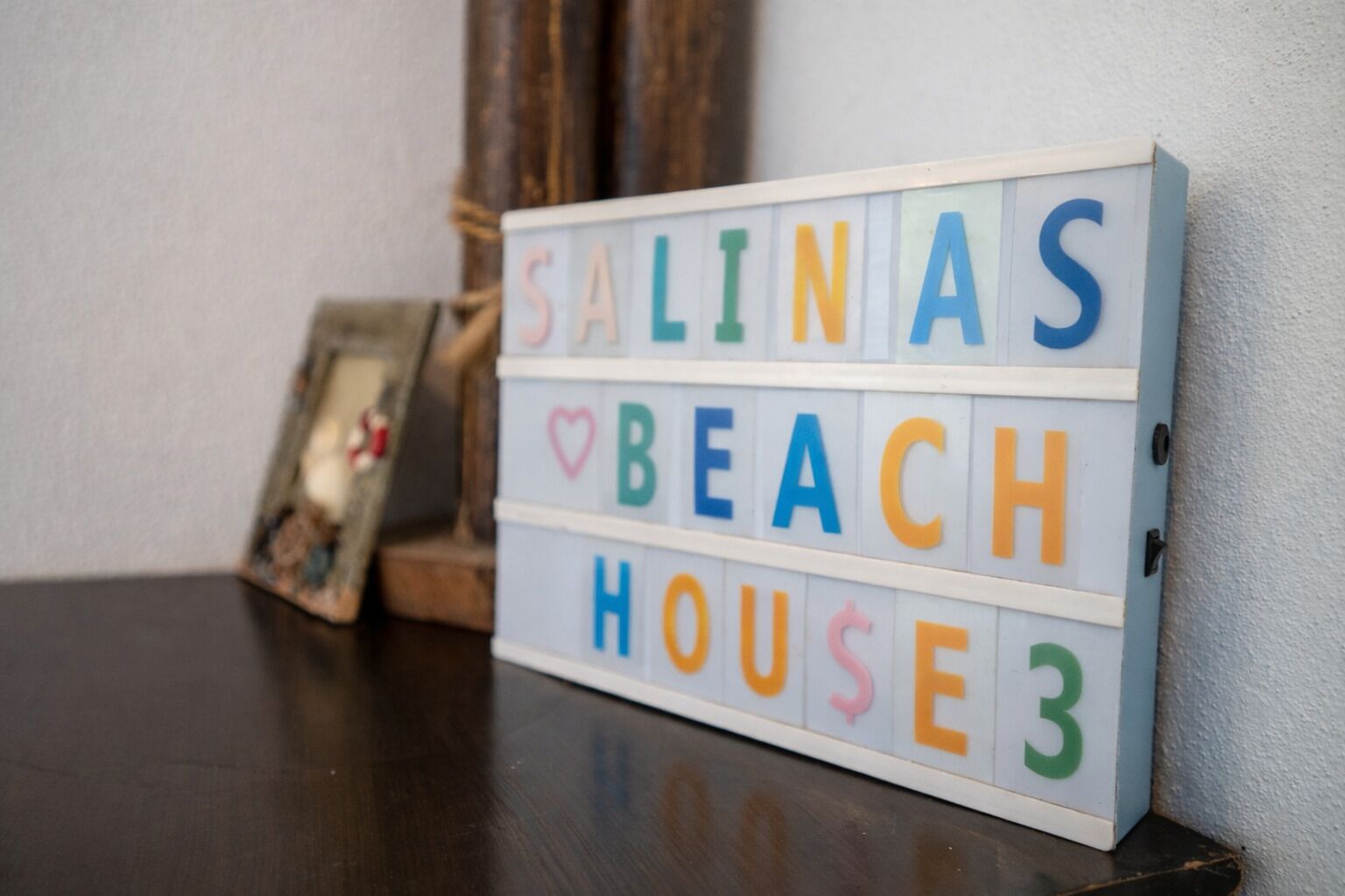 Una caja de luz con el texto "SALINAS BEACH HOUSE" en letras coloridas.