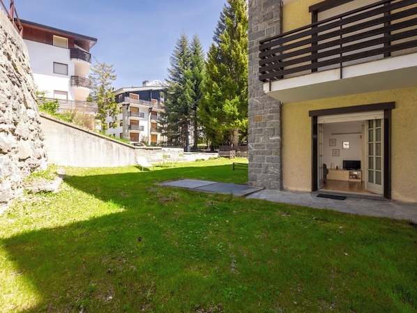 Un bâtiment moderne avec une façade en pierre, un balcon et une cour verdoyante.