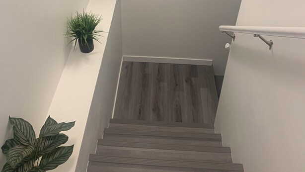 A staircase with wooden steps, a handrail, and a framed picture on the wall. - Friendly extended stay and comfort (Winnipeg)