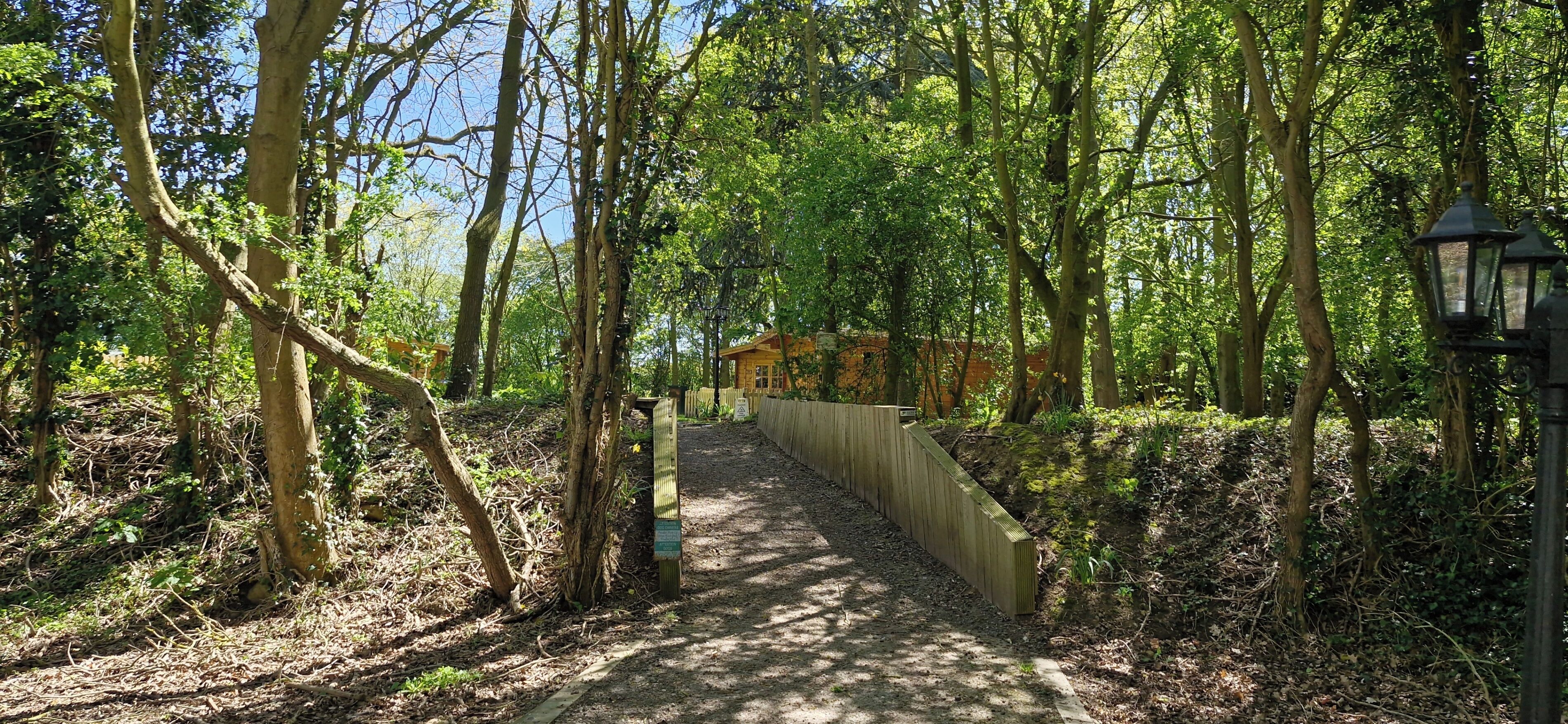 A forested path leading to a building with a sign.