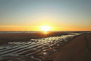 A beach with a sunset, wind turbines, and wet sand patterns. - Snowdrop Lodge Dog friendly Nr Sutton on Sea (Alford)