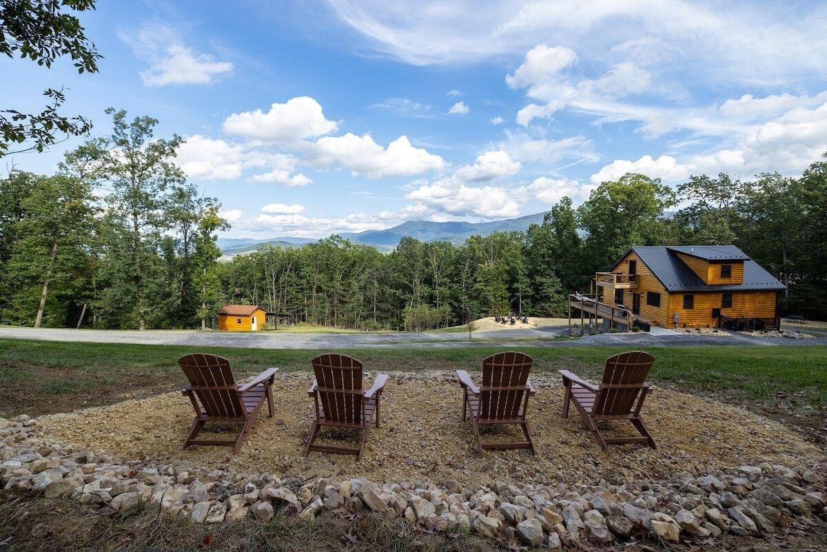 A cabin with a deck and a view of a forest and mountains.