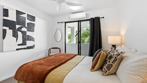 Une chambre d’hôtel avec un lit, une chaise, une fenêtre avec des rideaux et un mur orné d’une œuvre d’art géométrique.