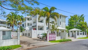 Un immeuble résidentiel moderne à plusieurs étages, doté de balcons, d’une entrée sécurisée et d’un panneau indiquant un centre de vaccination.