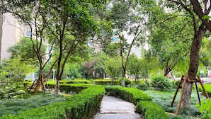 A paved pathway in a park with neatly trimmed hedges and trees. - Tyms Xujiahui Premium 2BR APT Metro (Shanghai)
