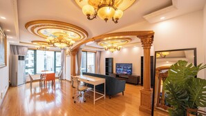 A spacious living area with a wooden floor, a dining table with chairs, a sofa, and a large plant. - Tyms Xujiahui Premium 2BR APT Metro (Shanghai)