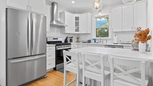 Una cocina moderna con armarios blancos, electrodomésticos de acero inoxidable y una isla central con asientos.