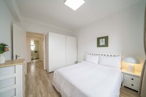 A bedroom with a bed, bedside table, lamp, and a framed picture on the wall. - Tyms Family 4BR 2BA APT Residence (Shanghai)