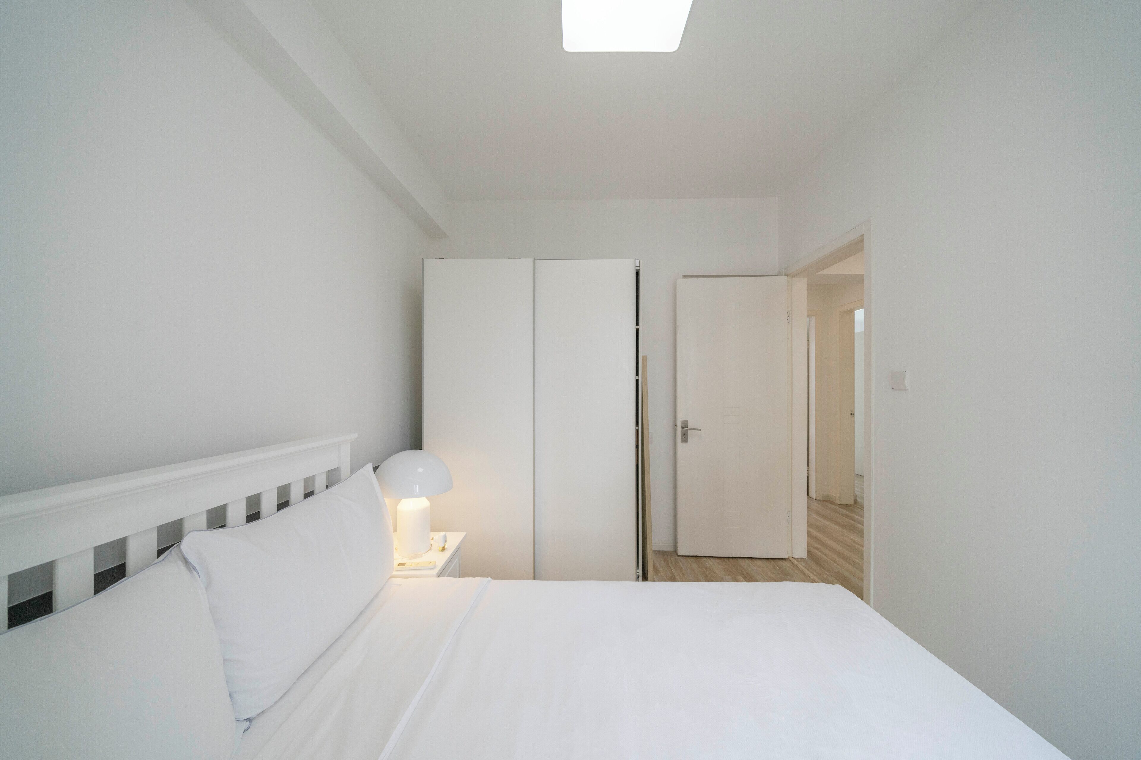 A bedroom with a bed, a nightstand, a lamp, and a wardrobe.