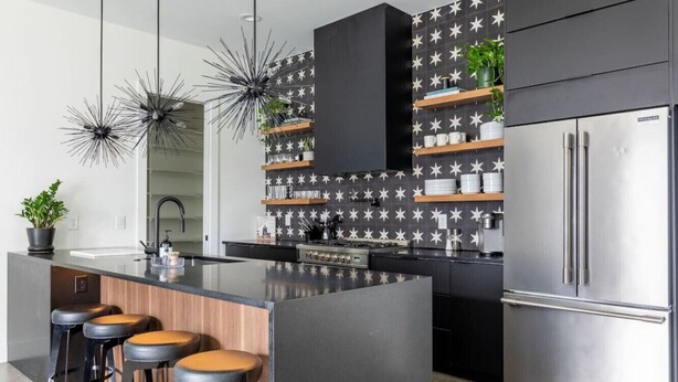 A modern kitchen with a central island, bar stools, a built-in oven, and a stainless steel refrigerator. - Modern Oasis: Rooftop Sunsets & City Lights! (Nashville)